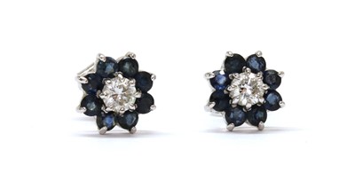 Lot 1285 - A pair of white gold diamond and sapphire cluster earrings