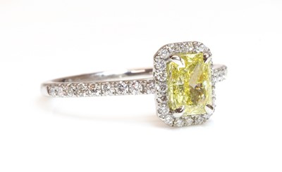 Lot 454 - A platinum fancy yellow diamond and diamond halo cluster ring