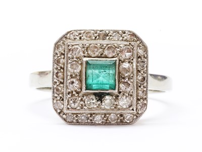 Lot 1264 - A white gold emerald and diamond cluster ring
