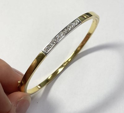 Lot 325 - An 18ct two colour gold diamond set hinged bangle