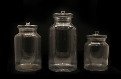 Lot 128 - A set of three graduated clear glass lidded jars