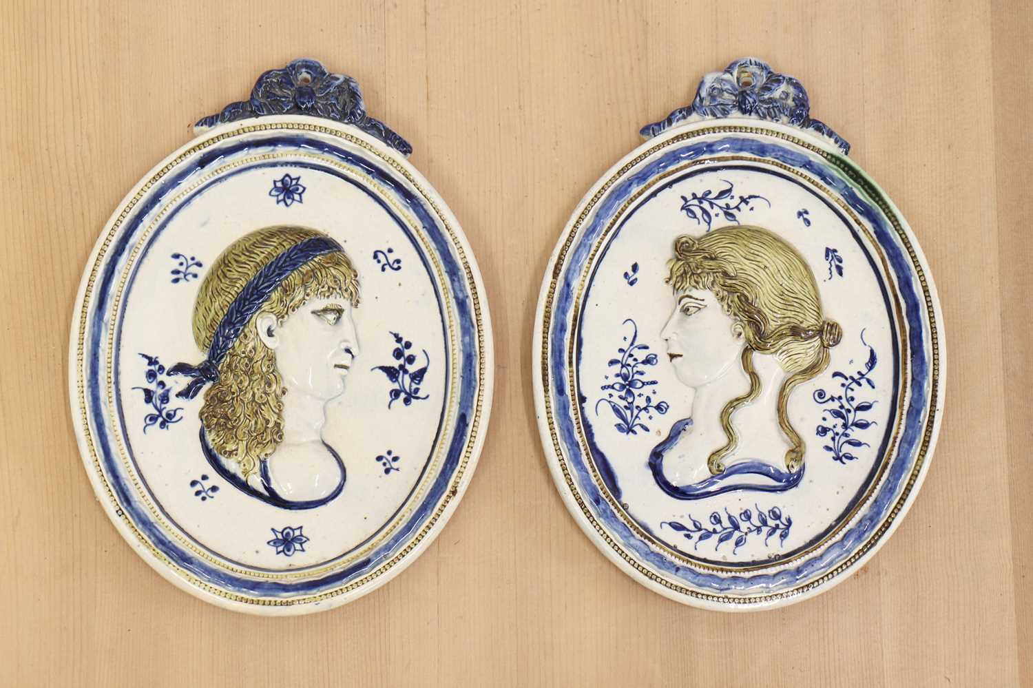 Lot 440 - A pair of oval moulded pottery plaques