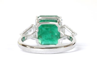Lot 1190 - A white gold three stone emerald and diamond ring