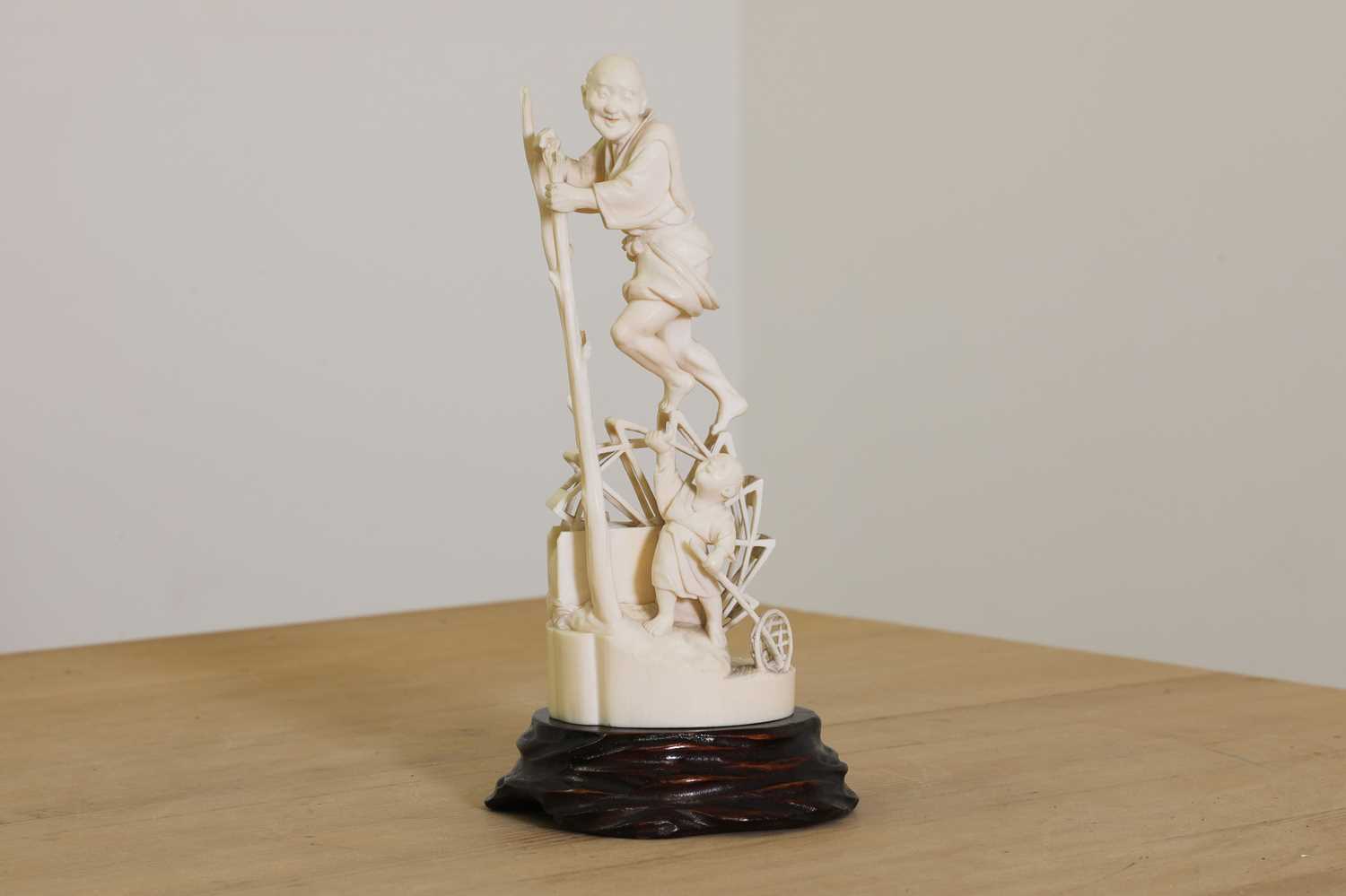 Lot 176 - A Japanese solid carved ivory figure of a man turning a waterwheel