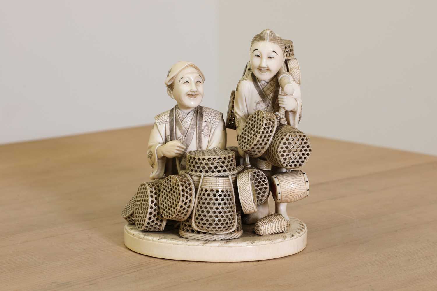 Lot 163 - A Japanese sectional carved ivory group of two basket sellers
