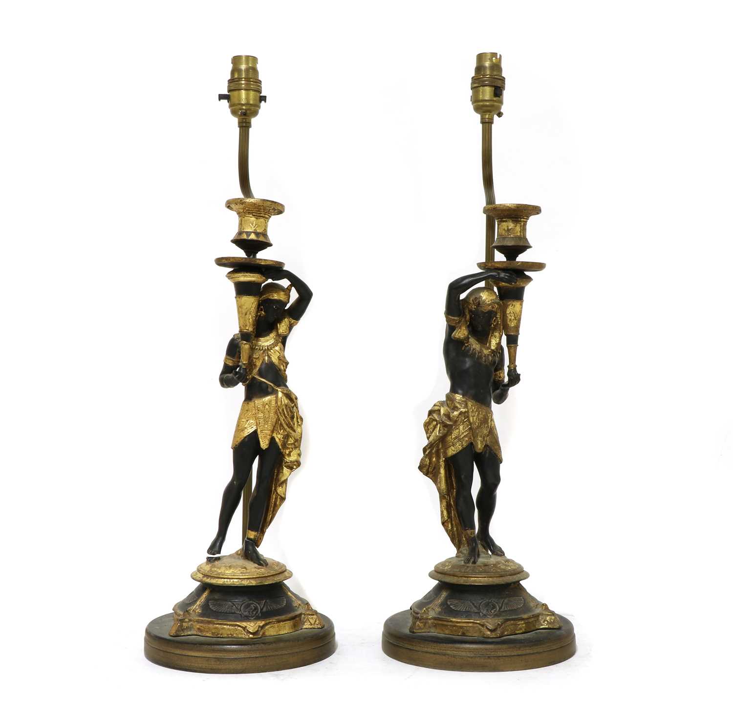 Lot 202 - A pair of Egyptian Revival figurative parcel-gilt candlestick lamps
