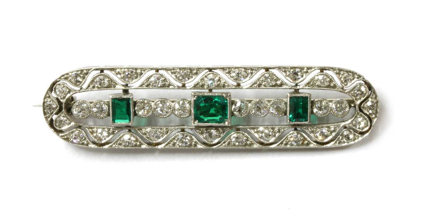 Lot 1061 - An early 20th century white gold emerald and diamond brooch