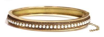 Lot 38 - A Victorian Etruscan revival split pearl flat section hinged bangle, c.1870