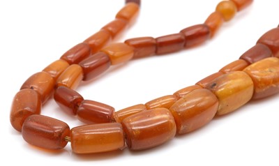 Lot 133 - A single row graduated amber barrel shaped bead necklace