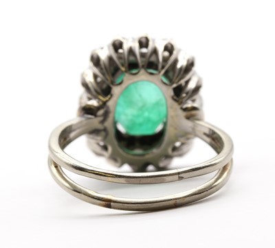 Lot 230 - A white gold emerald and diamond cluster ring