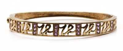 Lot 178 - A 9ct gold pink sapphire set hinged oval bangle