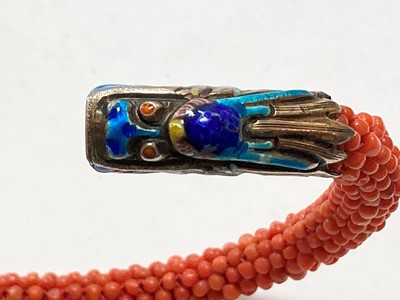Lot 86 - A Chinese silver enamel and coral bead bangle