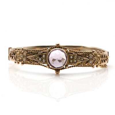 Lot 28 - An Edwardian gold amethyst and split pearl oval hinged bangle