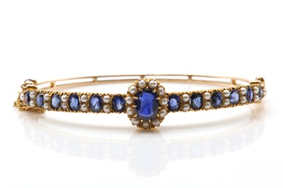 Lot 91 - An Edwardian gold sapphire and pearl bangle