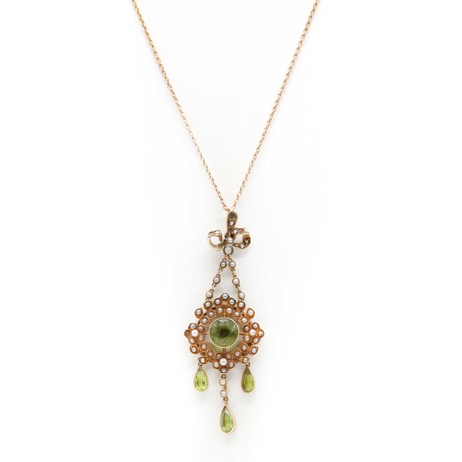 Lot 104 - An Edwardian gold peridot and split pearl wreath form pendant