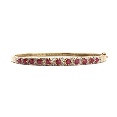 Lot 64 - A 9ct gold ruby and diamond hinged bangle