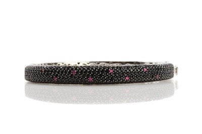 Lot 126 - An 18ct white gold black gemstone and ruby pavé set hinged 'Fantasia' bangle, by Roberto Coin, c.2005