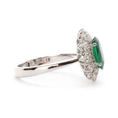 Lot 106 - A white gold emerald and diamond cluster ring