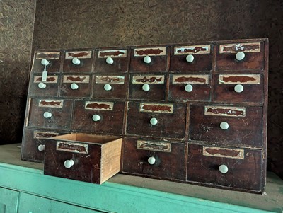 Lot 421 - ☘ A pharmacist's bank of stained pine medicine drawers