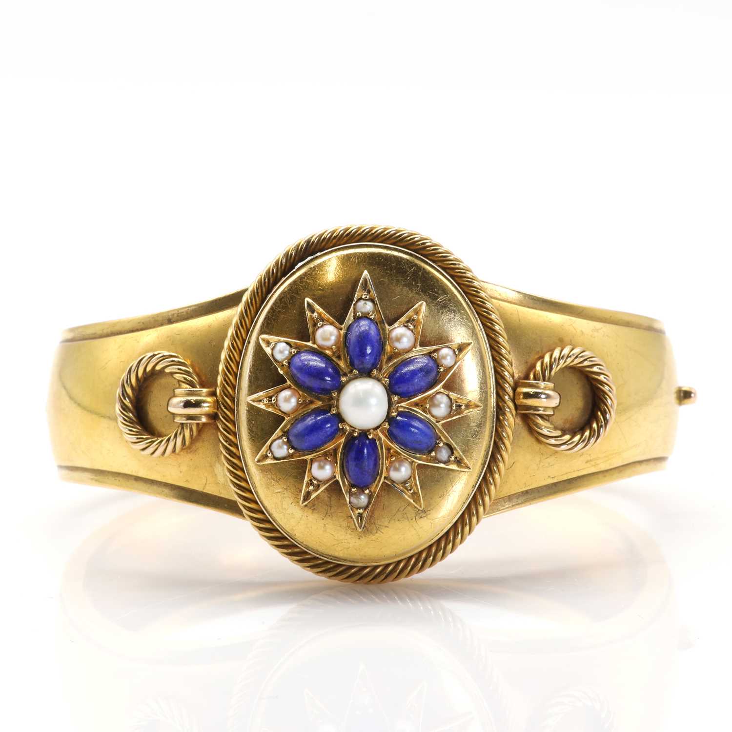 Lot 11 - A Victorian gold, lapis lazuli and pearl hinged bangle with double-sided locket