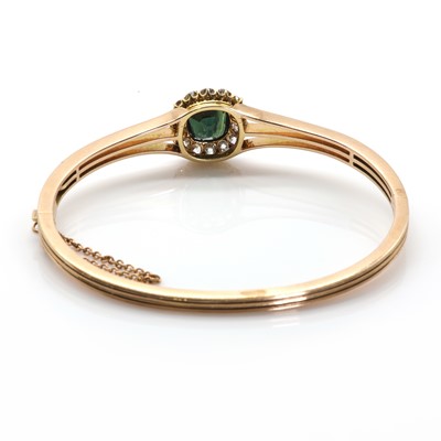 Lot 23 - An early 20th century green sapphire and diamond cluster hinged bangle