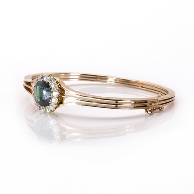 Lot 23 - An early 20th century green sapphire and diamond cluster hinged bangle