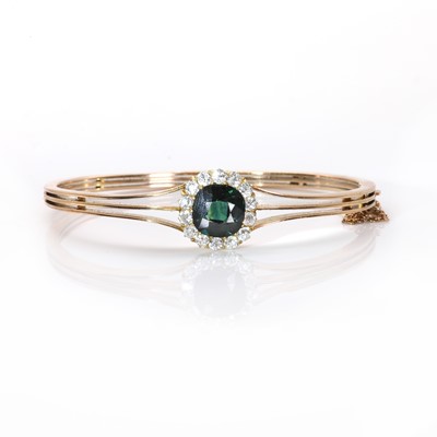 Lot 23 - An early 20th century green sapphire and diamond cluster hinged bangle
