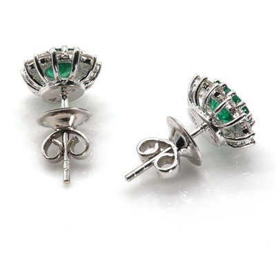 Lot 104 - A pair of white gold emerald and diamond oval cluster stud earrings
