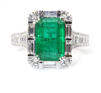 Lot 183 - A white gold emerald and diamond cluster ring
