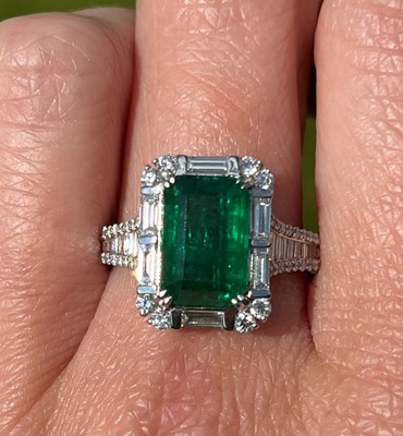 Lot 183 - A white gold emerald and diamond cluster ring