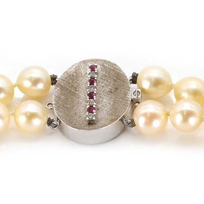 Lot 159 - A two-row uniform pearl necklace with ruby and diamond set textured clasp