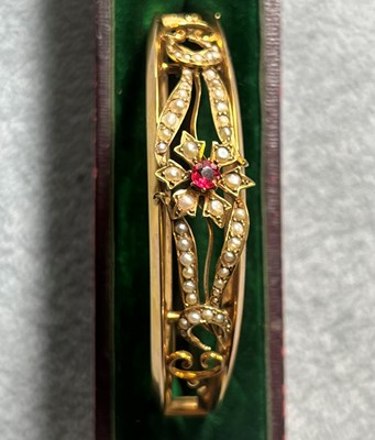 Lot 28 - An Edwardian gold split pearl hinged bangle