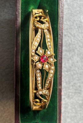 Lot 28 - An Edwardian gold split pearl hinged bangle