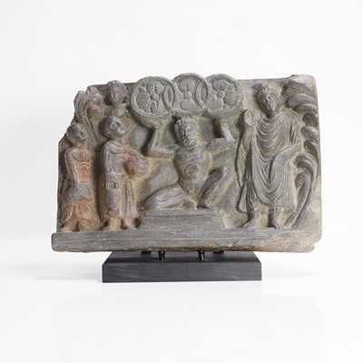 Lot 209 - A grey schist relief panel of Atlas holding the three wheels