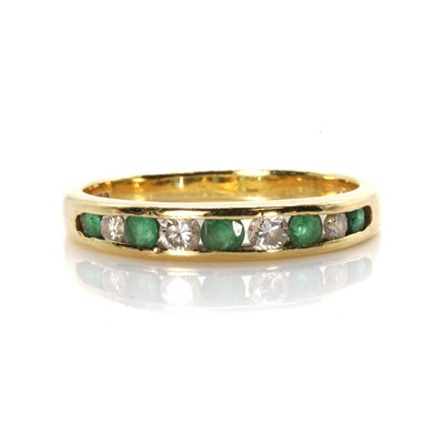 Lot 123 - An 18ct gold emerald and diamond half eternity ring