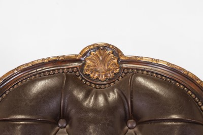 Lot 9 - A pair of buttoned leather and parcel-gilt wooden armchairs