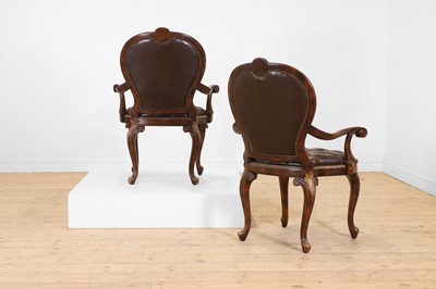 Lot 9 - A pair of buttoned leather and parcel-gilt wooden armchairs