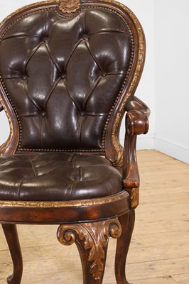 Lot 9 - A pair of buttoned leather and parcel-gilt wooden armchairs