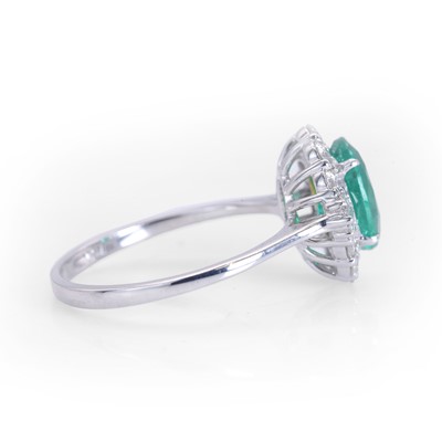 Lot 89 - An 18ct white gold emerald and diamond cluster ring