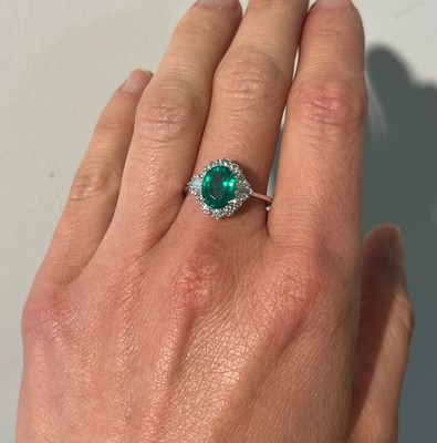 Lot 89 - An 18ct white gold emerald and diamond cluster ring