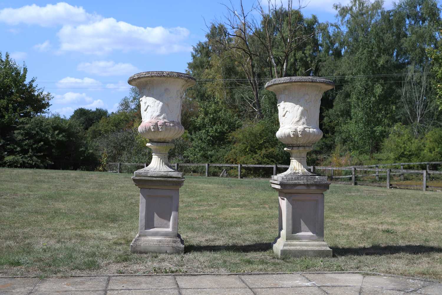 Lot 583 - A pair of composite stone garden urns on plinths