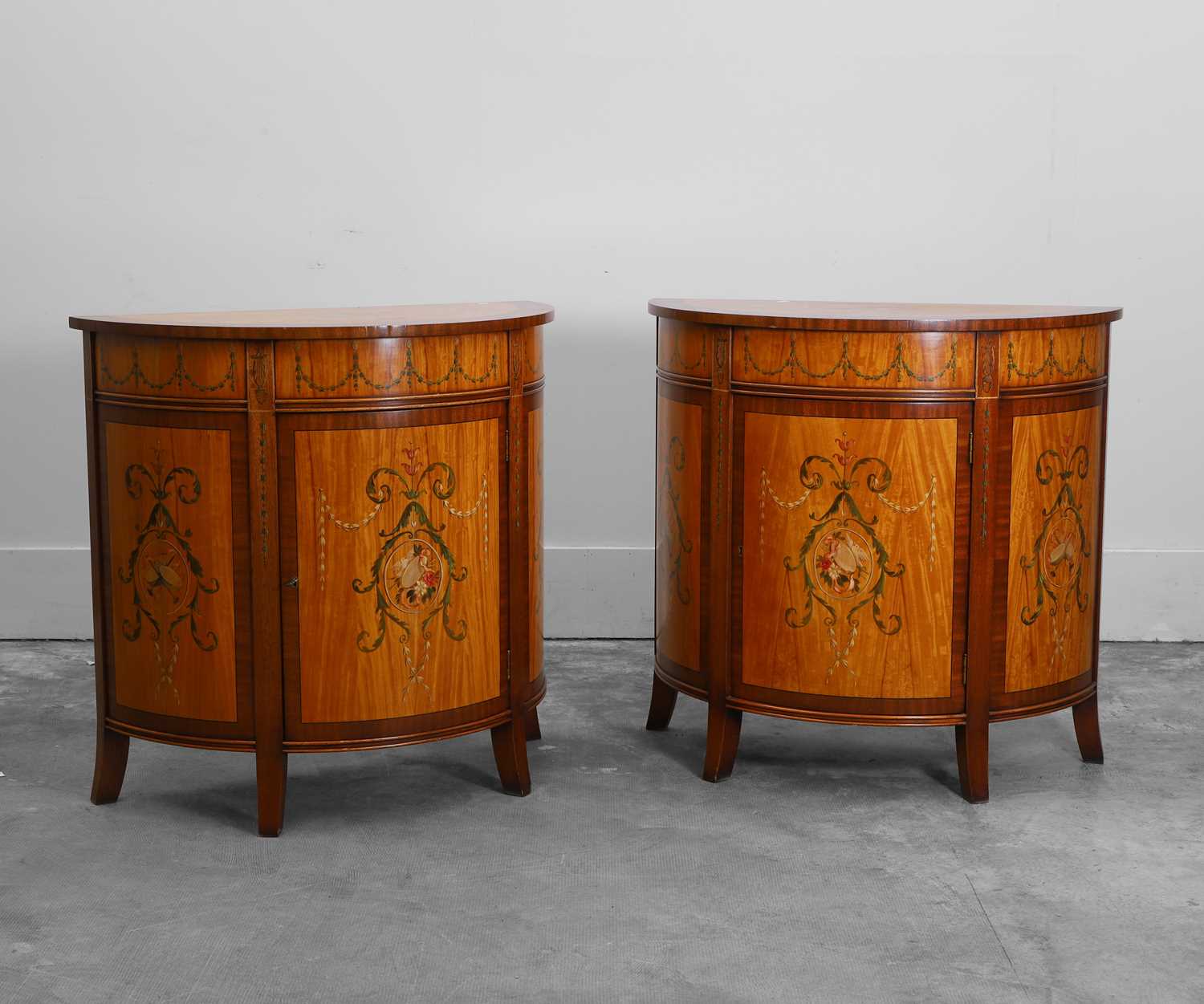 Lot 527 - A pair of stainwood and mahogany painted demilune cabinets